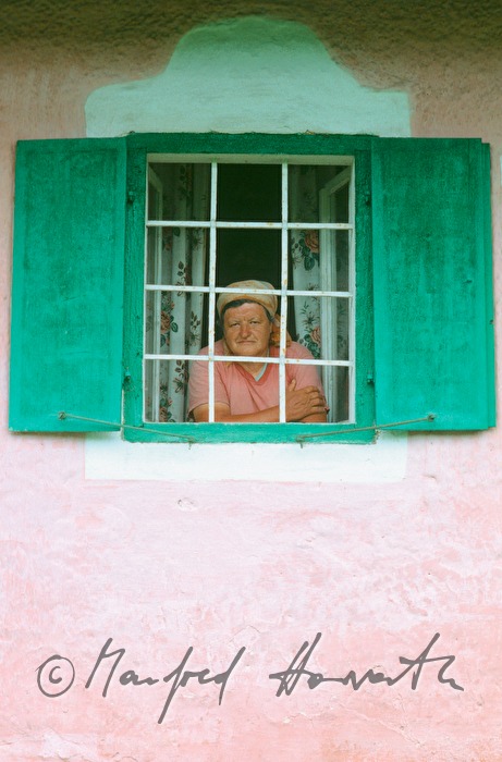 Bäuerin schaut aus dem Fenster ihres Hauses