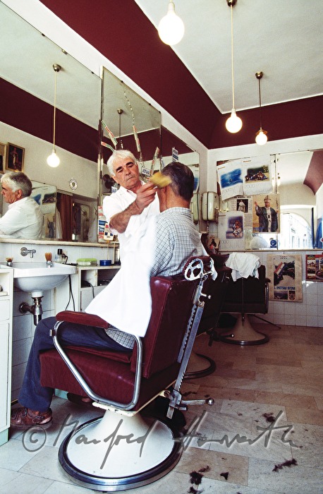Friseur rasiert Kunden