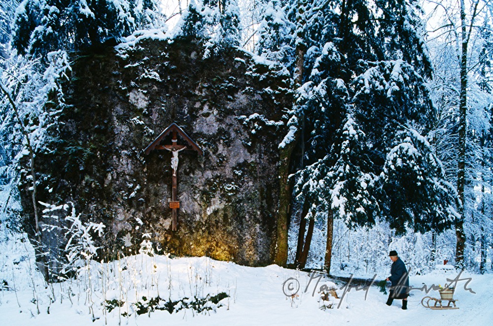 Frau mit Schlitten bei Wegkreuz