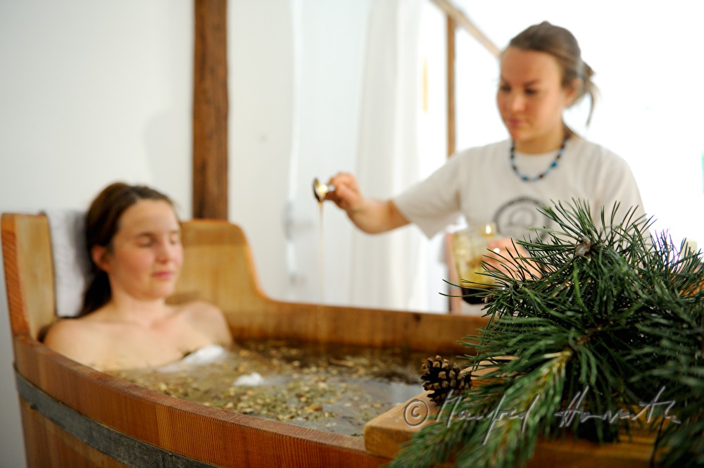 Frau nimmt ein Wellness-Latschen-Bad im Holzzuber