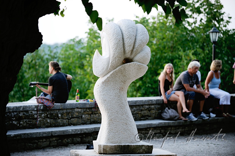 Gitarrespielerin neben Skulptur auf der Stadtmauer