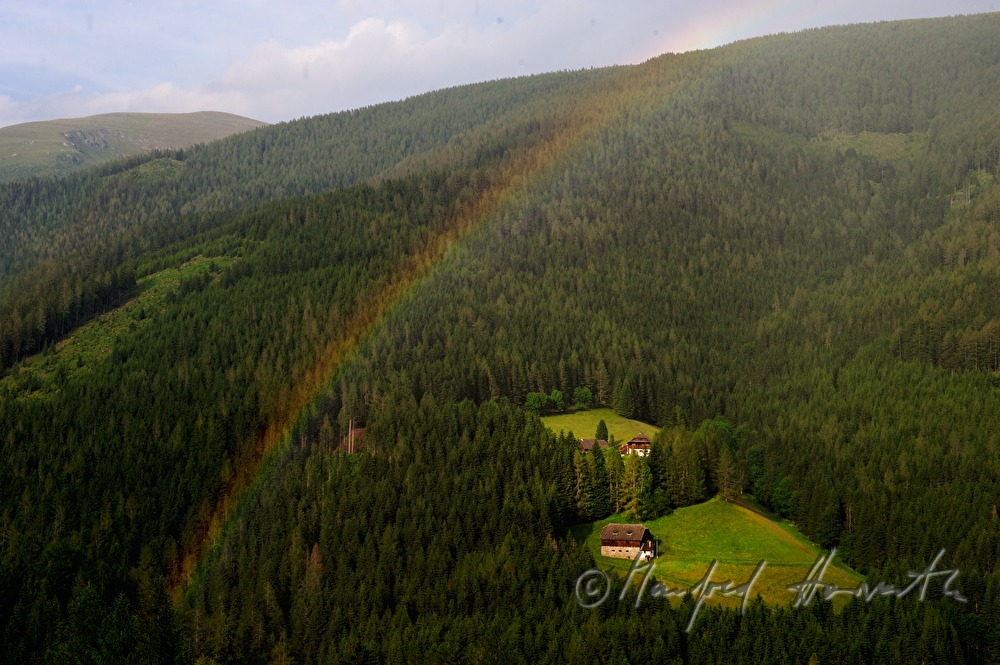 Bergbauernhöfe im Wald und Regenbogen