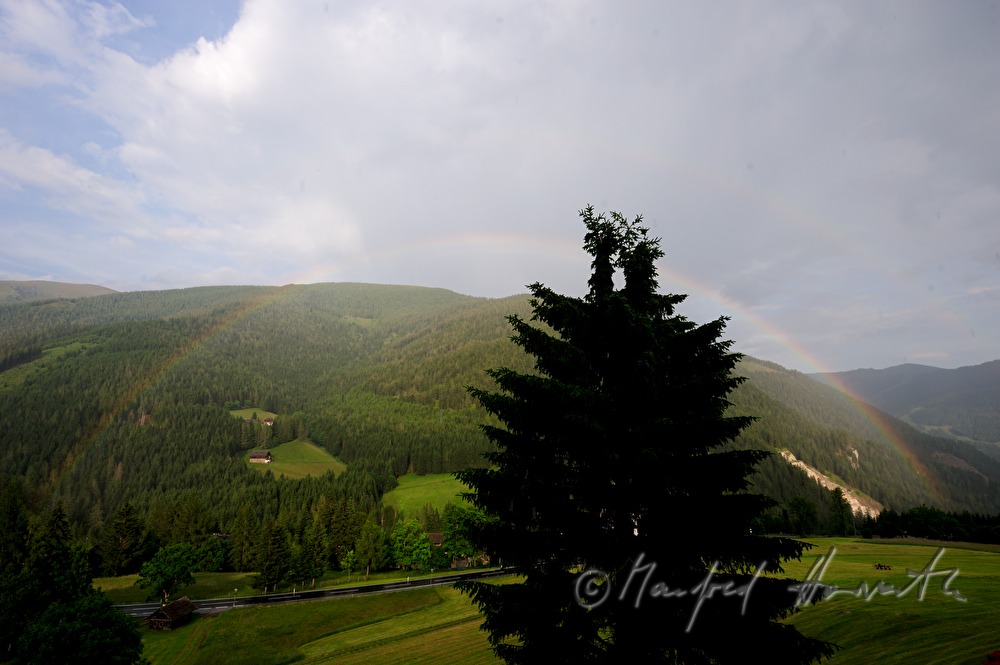 Bergbauernhöfe im Wald und Regenbogen