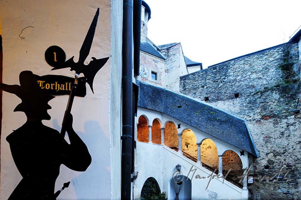 gedeckter Stiegenaufgang mit Ritterstatue im Innenhof