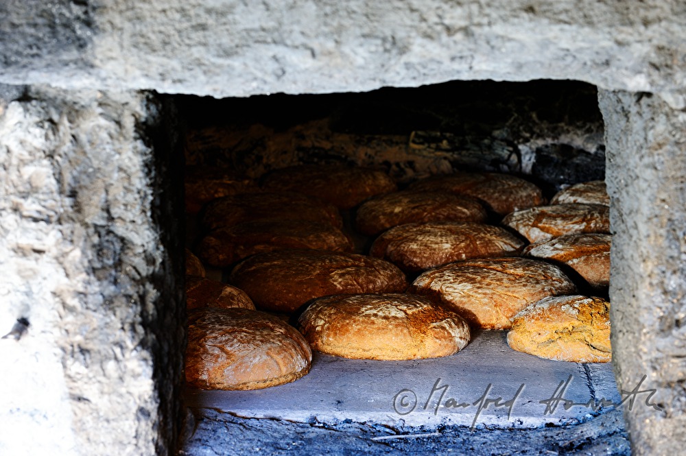 Backen von Holzofenbrot im feuerbetriebenen Backhaus