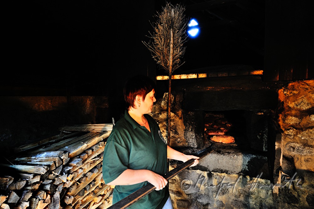Backen von Holzofenbrot im feuerbetriebenen Backhaus