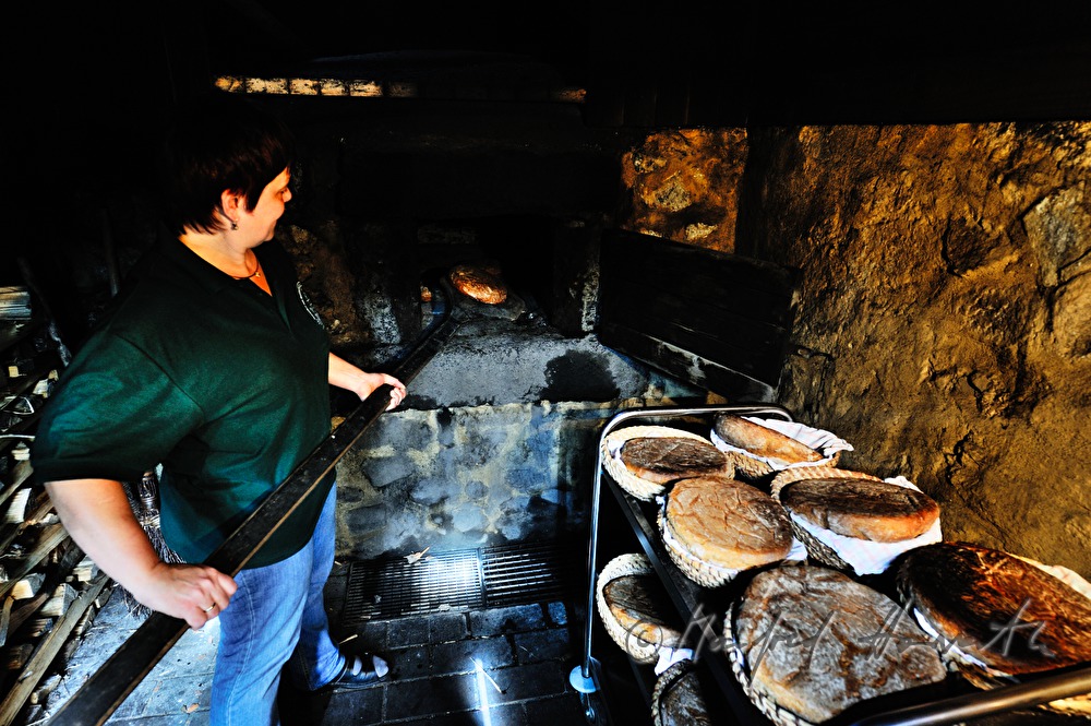 Backen von Holzofenbrot im feuerbetriebenen Backhaus