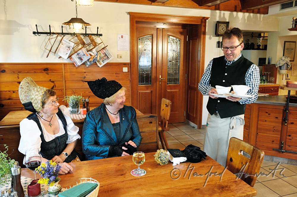 Frauen in Goldhauben-Tracht werden bewirtet
