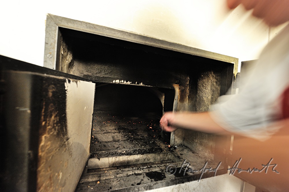 Reinigung des Holzofens von Asche vor dem Brotbacken