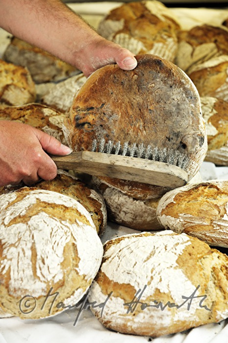 Abbürsten von frisch gebackenem Holzofenbrot