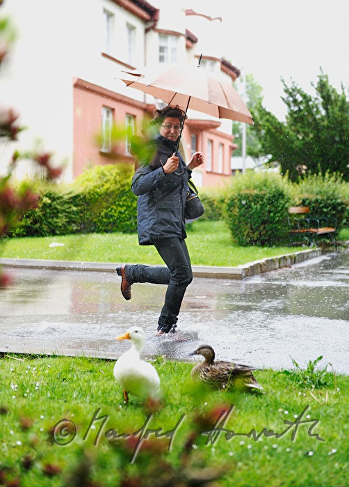 Frau läuft im Regen mit Regenschirm