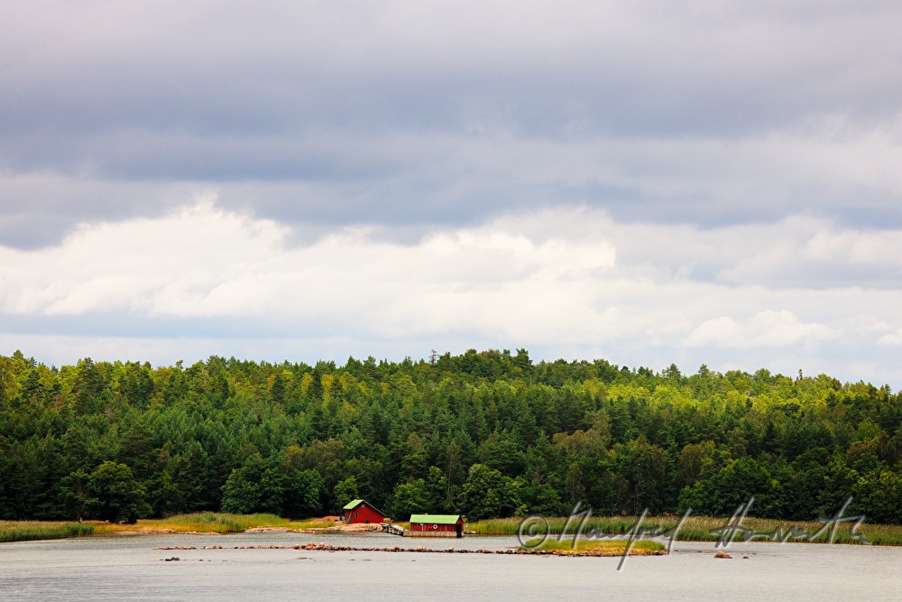 kleine Insel mit schwedenrotem Haus und Bootsanlegestelle