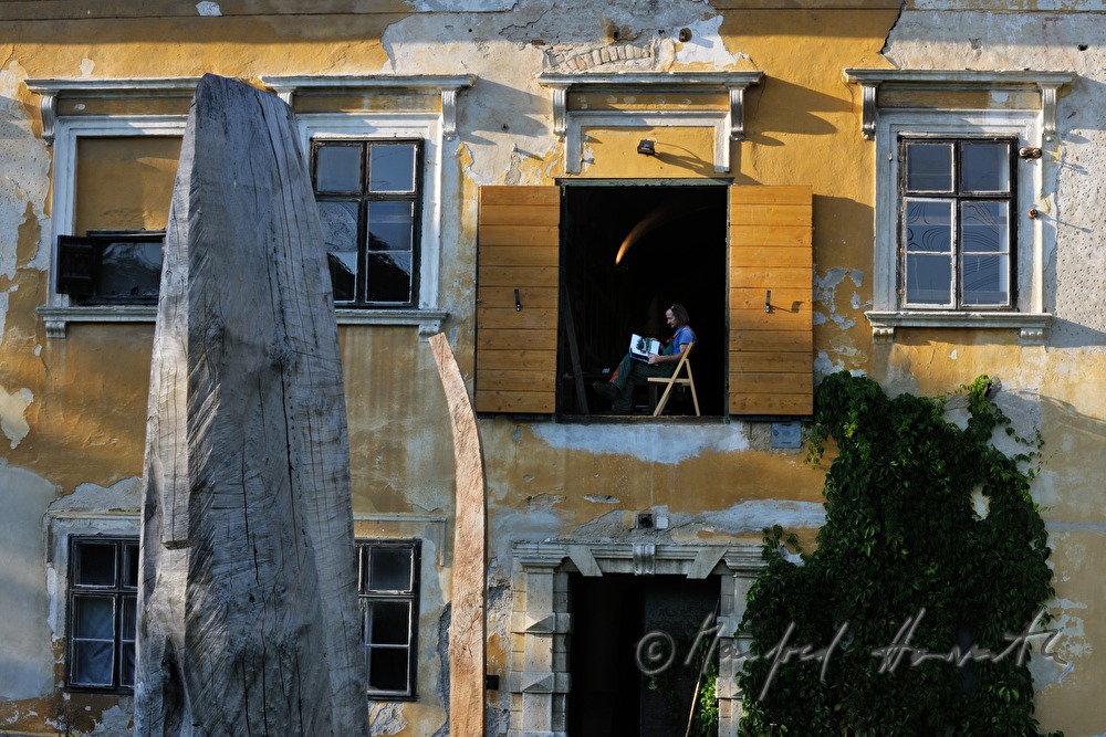 Johann Feilacher mit Baum-Skulpturen am Fenster seines Ateliers