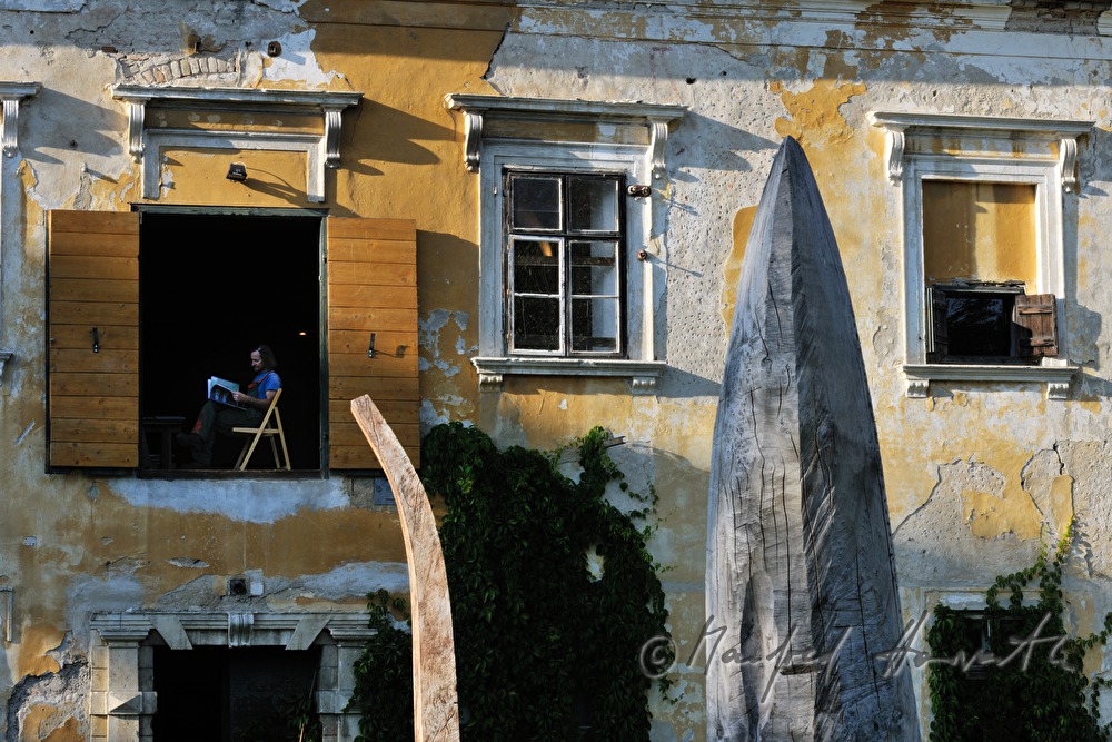 Johann Feilacher mit Baum-Skulpturen am Fenster seines Ateliers