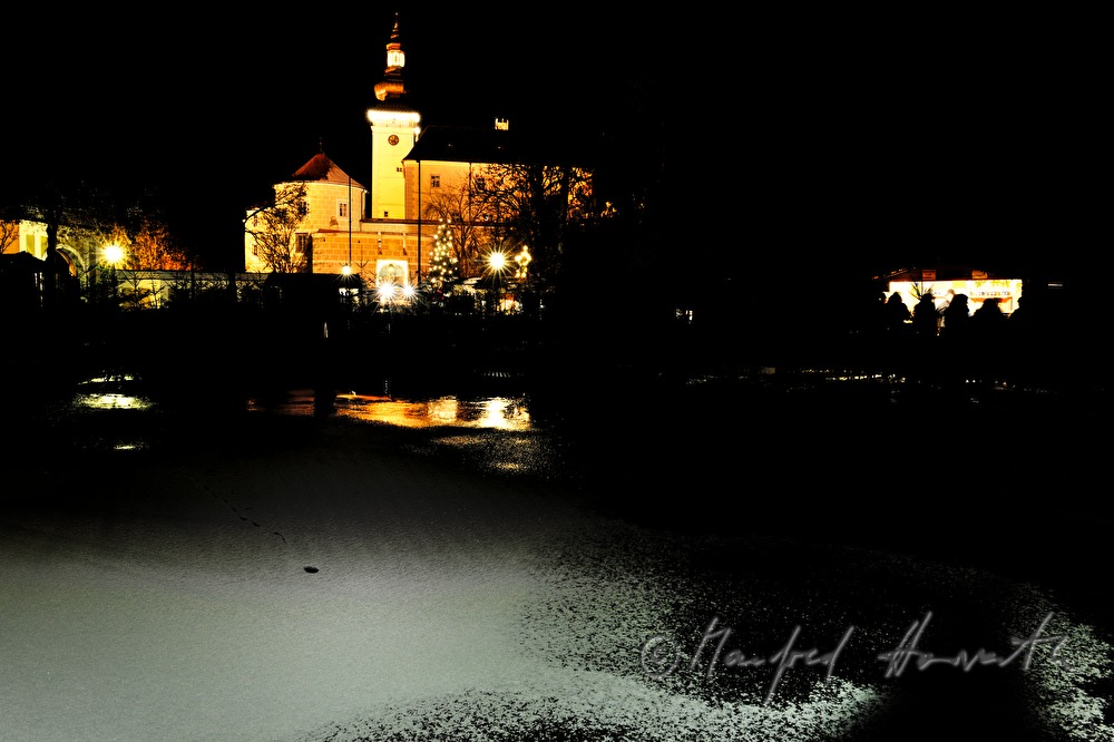gefrorener Teich und Stand während des Adventmarktes