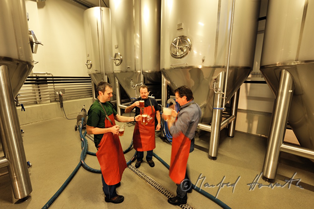 Braumeister und Arbeiter verkosten Bier im Keller