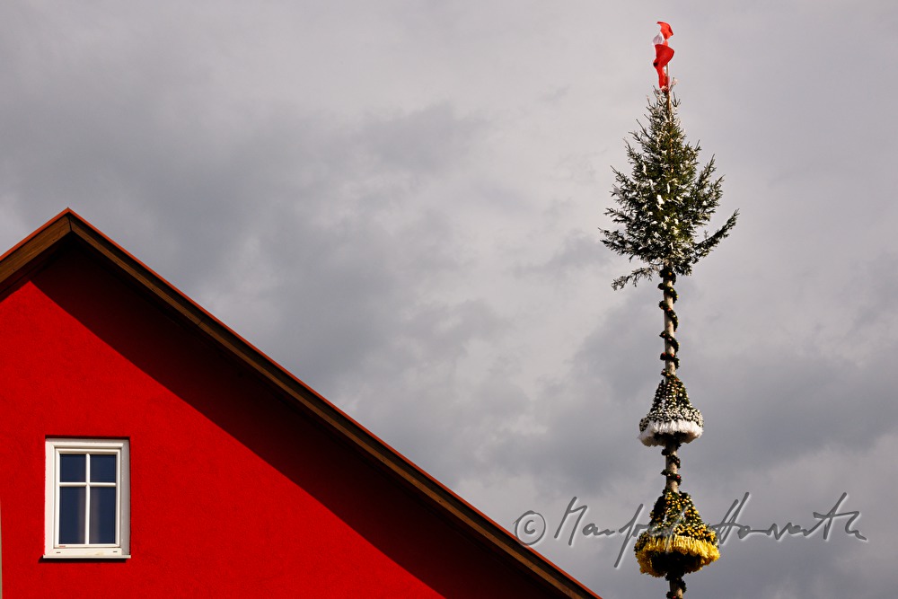 Maibaum und rotes Haus im Dorf