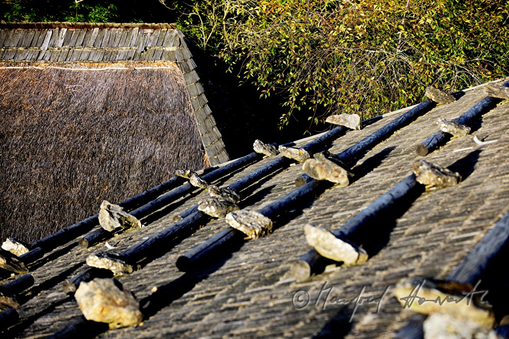 Bauernhaus mit Strohdach und Steinen auf dem Schindeldach