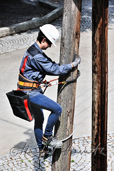 Elektromonteurin klettert auf einen Strommast
