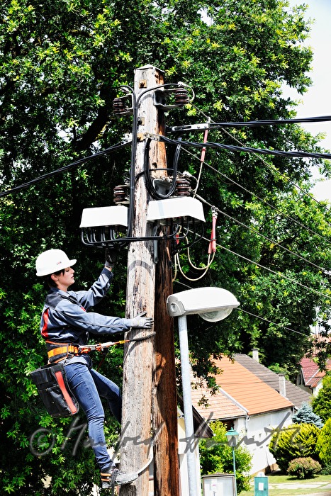 Elektromonteurin klettert auf einen Strommast