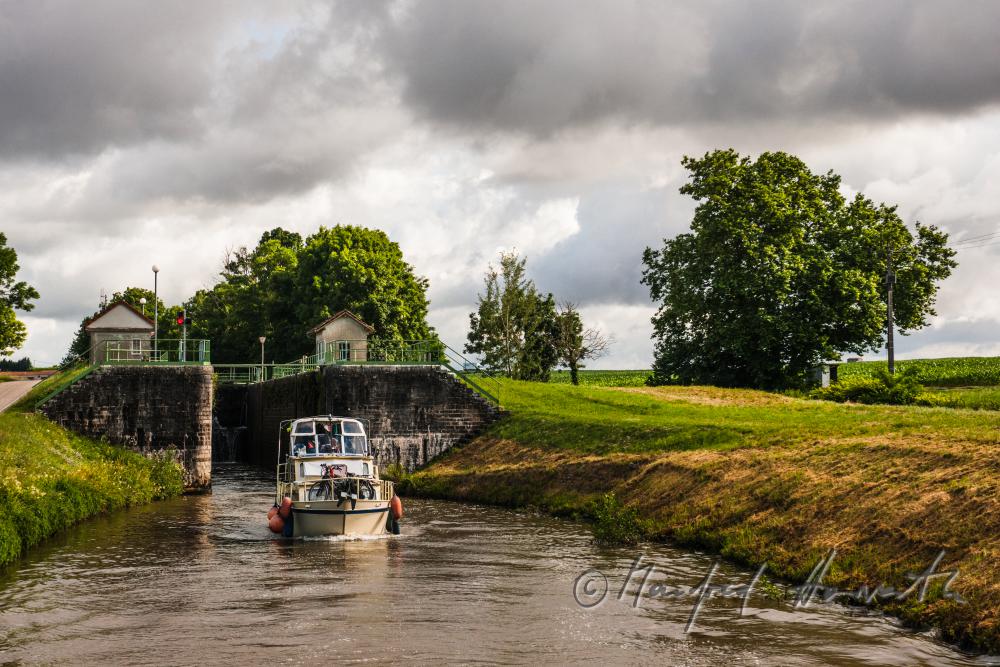 Hausboot kommt aus der Schleuse der Ortschaft Rully