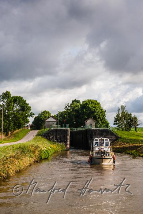Hausboot kommt aus der Schleuse der Ortschaft Rully