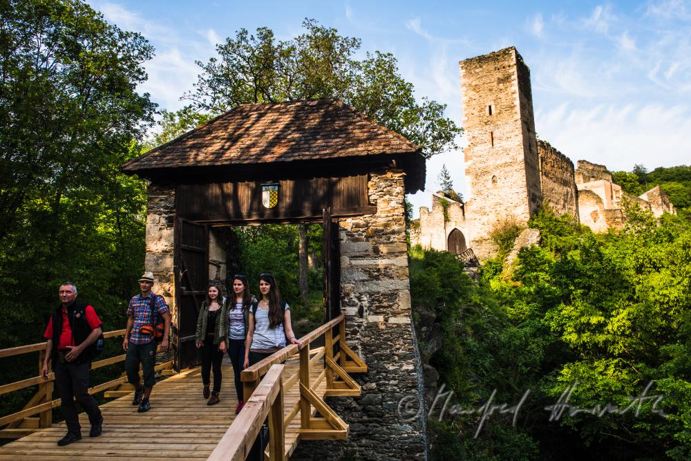Burg Kaja und Wanderer auf der Holzbrücke