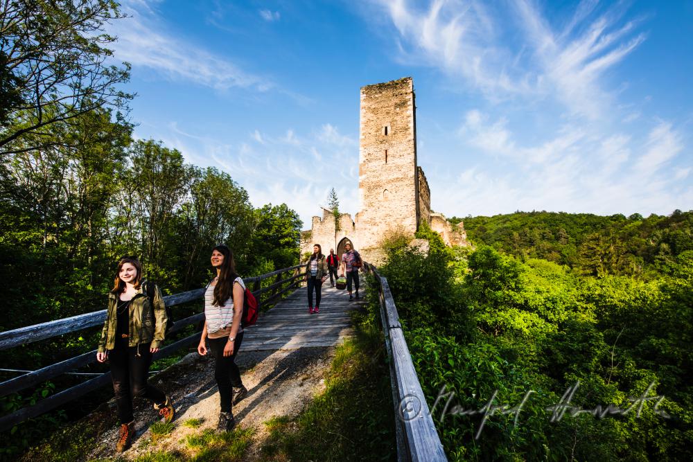 Burg Kaja und Wanderer auf der Holzbrücke