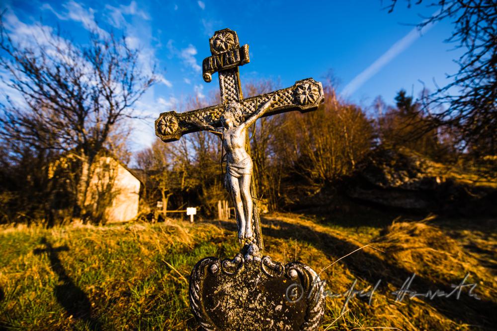 Grabkreuz bei einem Bauernhof im freien Feld