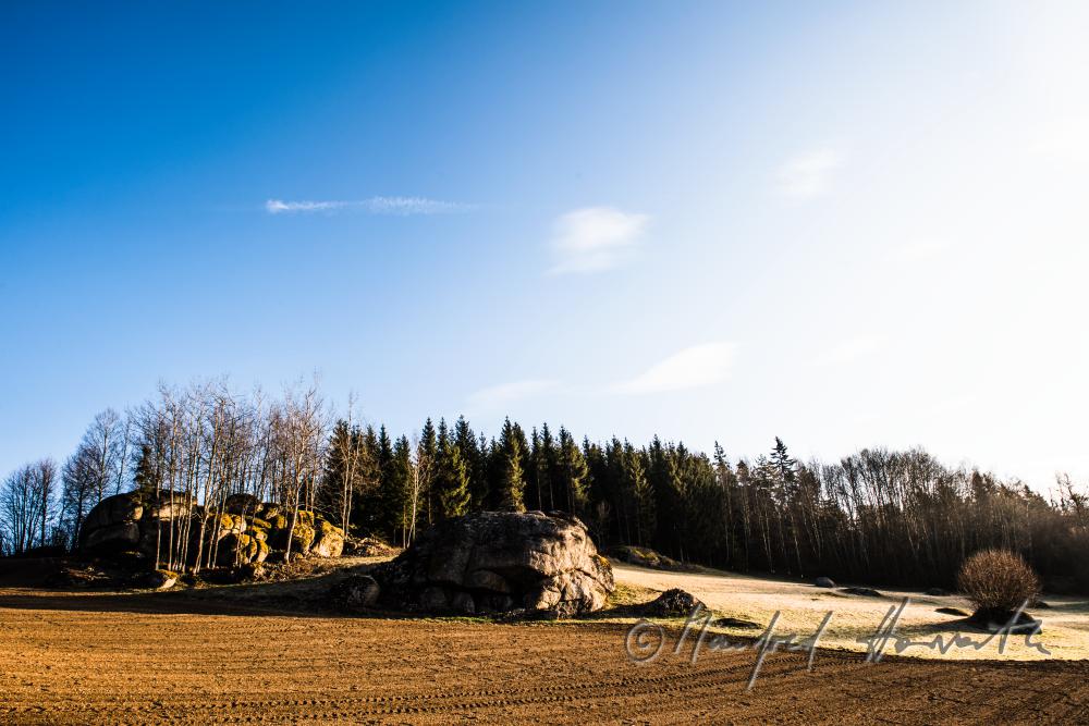 Granit-Findlinge am Waldrand bei einem Feld