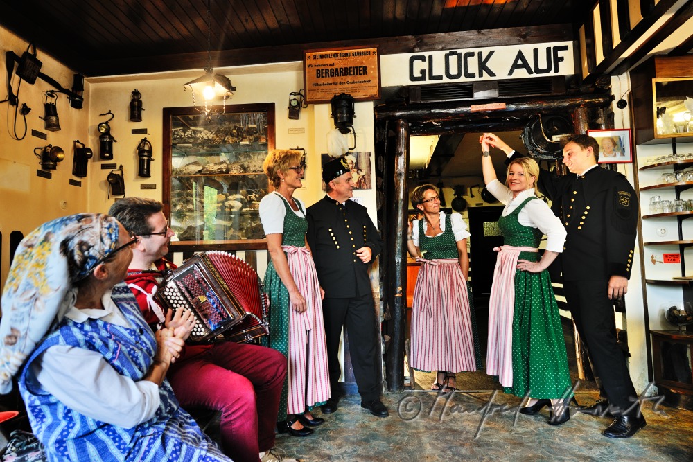 Frauen im Dirndl und Bergmänner tanzen im Bergmann-Museum