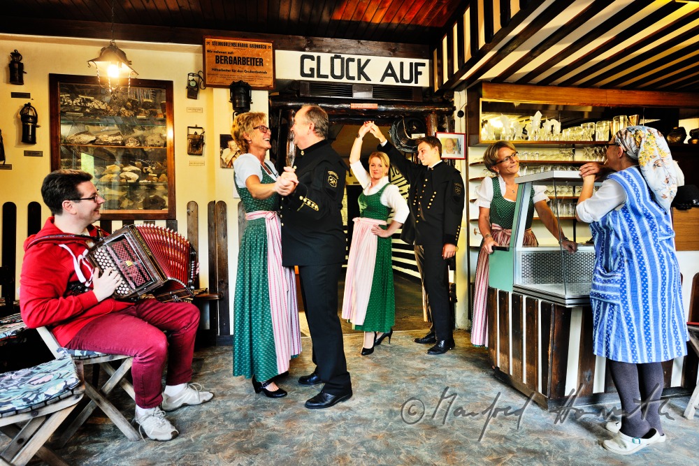 Frauen im Dirndl und Bergmänner tanzen im Bergmann-Museum